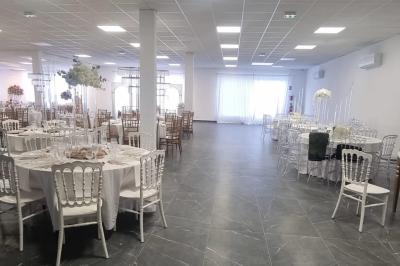 Salle de réception élégamment décorée avec des tables rondes, des chaises dorées et blanches, et des arrangements floraux.