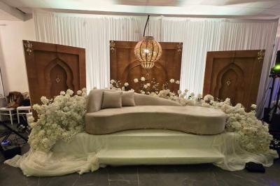 Salle de réception élégamment décorée avec des tables rondes, des chaises dorées et blanches, et des arrangements floraux.