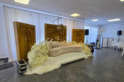 Salle de réception élégamment décorée avec des tables rondes, des chaises dorées et blanches, et des arrangements floraux.