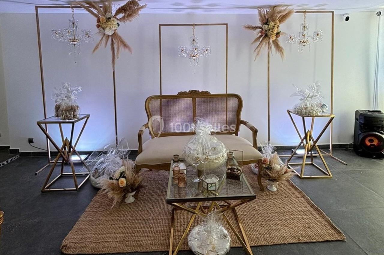 Salon décoré avec un canapé vintage, des tables dorées, des pampas et des cadeaux emballés sur un tapis en jute.
