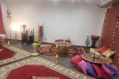 Salon décoré avec des tapis orientaux, un canapé doré, des coussins colorés et des éléments décoratifs traditionnels.