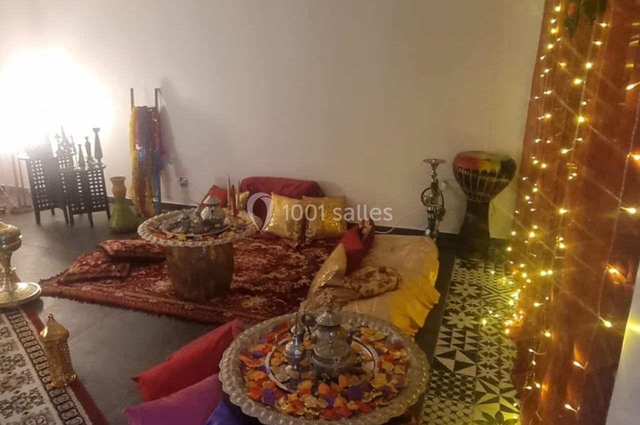 Espace intérieur décoré de coussins colorés, tapis, tables basses ornées et lumières tamisées dans un style oriental.