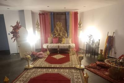 Salon décoré avec des tapis orientaux, un canapé doré, des coussins colorés et des éléments décoratifs traditionnels.