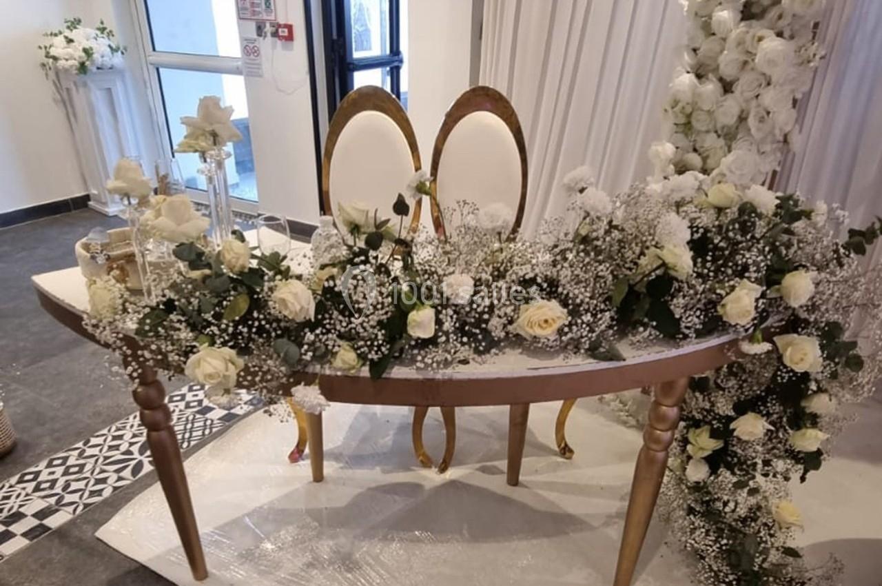 Table décorée de roses blanches et de gypsophiles, avec deux chaises élégantes, dans un cadre de cérémonie.