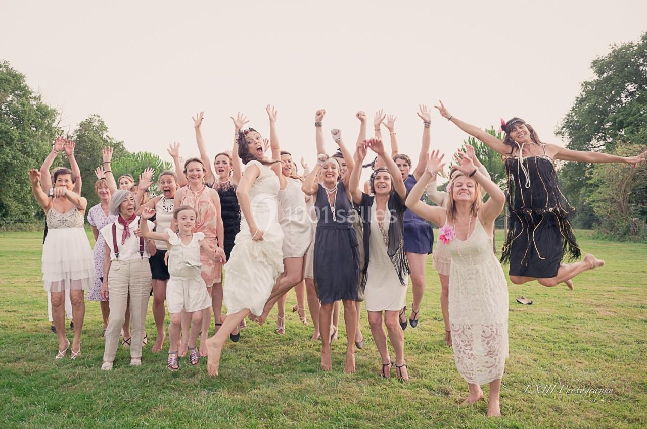 Un groupe de personnes souriantes saute en l'air dans un champ verdoyant par temps clair.