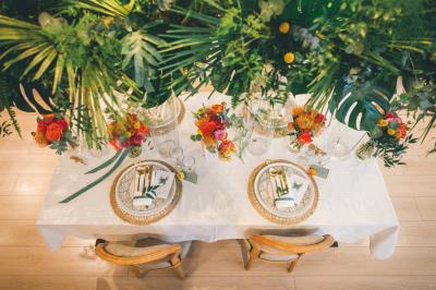 Miniature Angèle Event & Wedding #14 Salle de réception élégante avec tables dressées, chaises blanches et décorations florales sous un éclairage chaleureux.