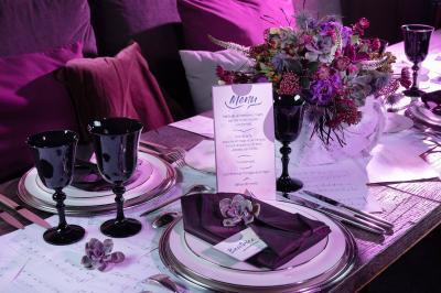 Miniature Angèle Event & Wedding #15 Salle de réception élégante avec tables dressées, chaises blanches et décorations florales sous un éclairage chaleureux.