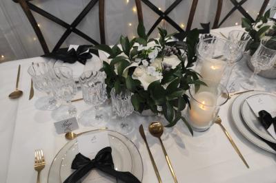 Miniature Angèle Event & Wedding #19 Salle de réception élégante avec tables dressées, chaises blanches et décorations florales sous un éclairage chaleureux.