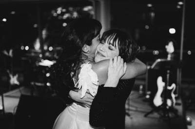 Miniature Angèle Event & Wedding #20 Salle de réception élégante avec tables dressées, chaises blanches et décorations florales sous un éclairage chaleureux.