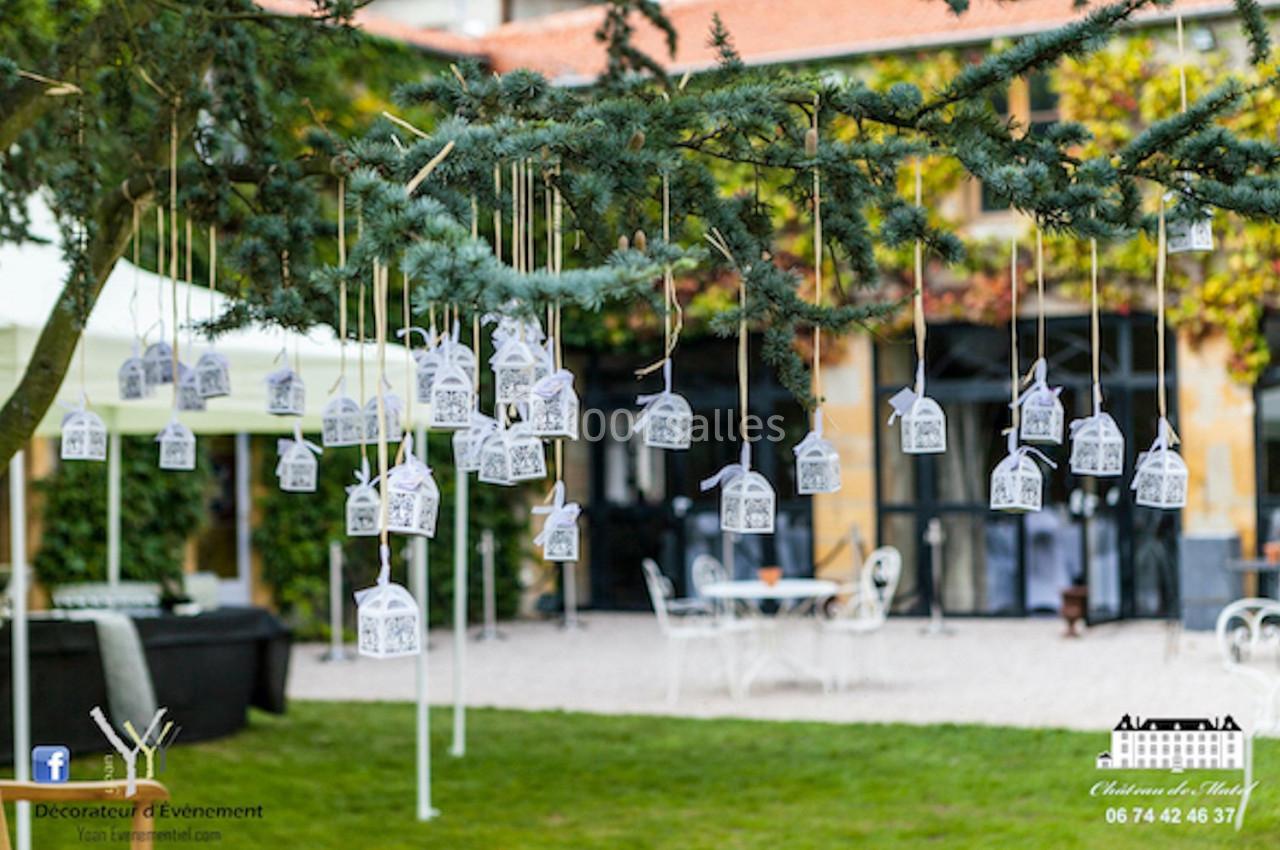 Location salle Roanne (Loire) - Château de Matel #22 Des petites lanternes blanches suspendues à un arbre décorent un espace extérieur devant un bâtiment.