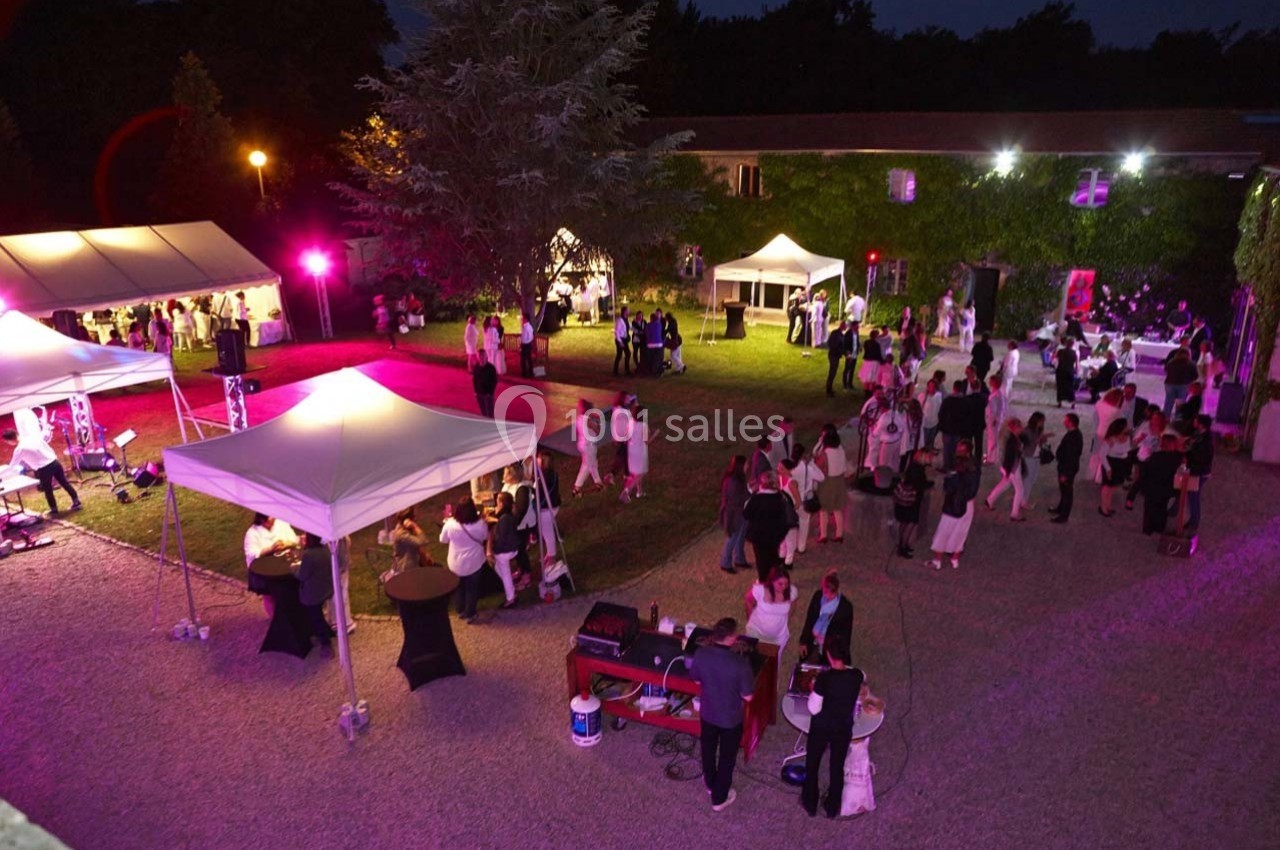 Location salle Roanne (Loire) - Château de Matel #18 Vue nocturne d'un événement en plein air avec des invités, des tentes éclairées et une ambiance festive.