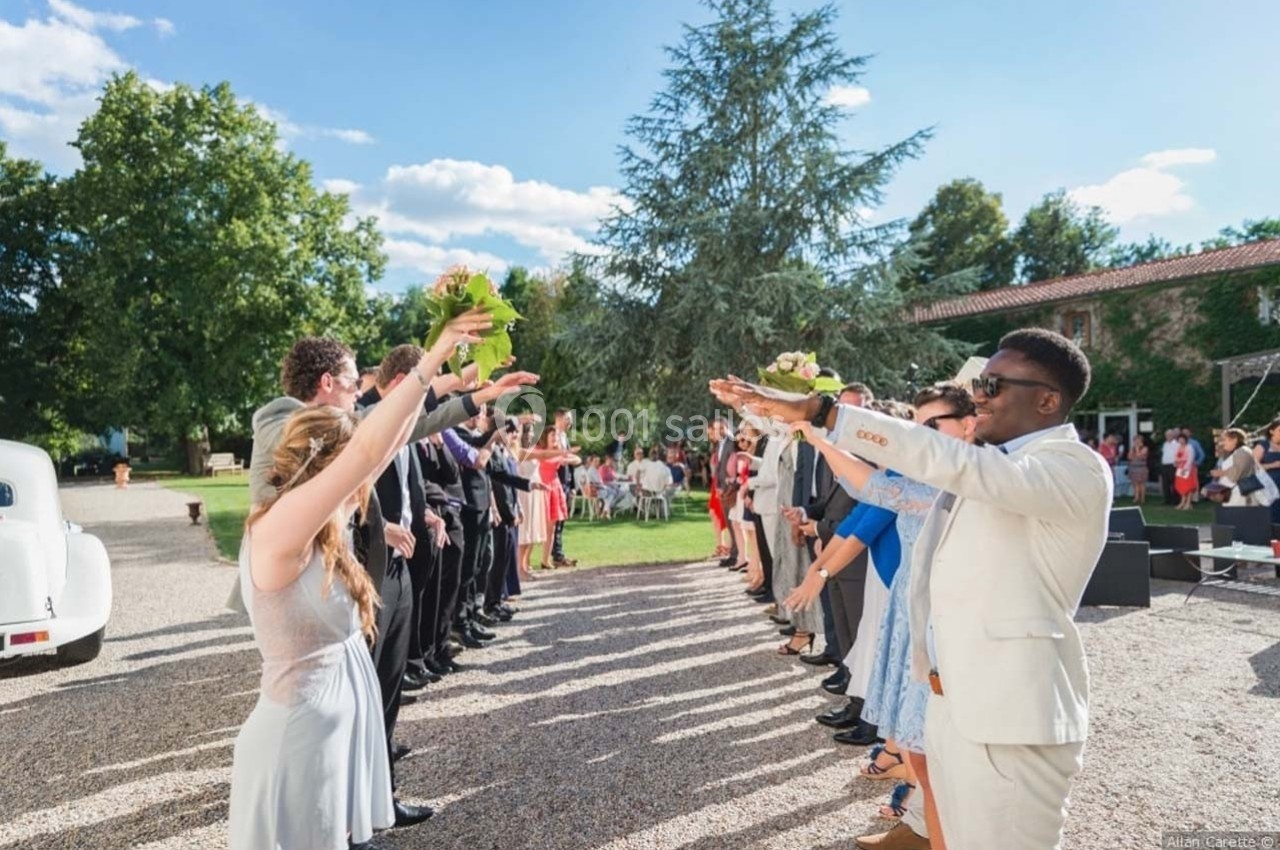 Location salle Roanne (Loire) - Château de Matel #2 Des invités forment une haie d'honneur en plein air, levant les bras pour accueillir un couple lors d'une cérémonie.