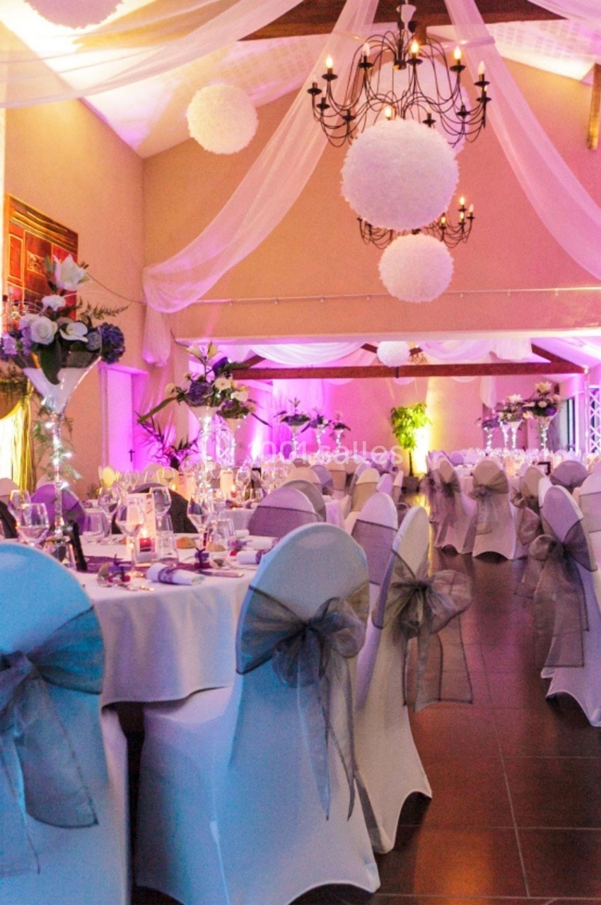 Location salle Roanne (Loire) - Château de Matel #9 Salle de réception décorée avec des tables dressées, des chaises ornées de nœuds gris et un éclairage rose tamisé.
