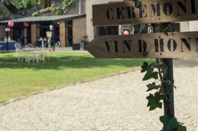 Miniature Location salle Roanne (Loire) - Château de Matel #4 Allée gravillonnée bordée de lanternes blanches menant à un jardin arboré, vue depuis un portail en fer forgé.