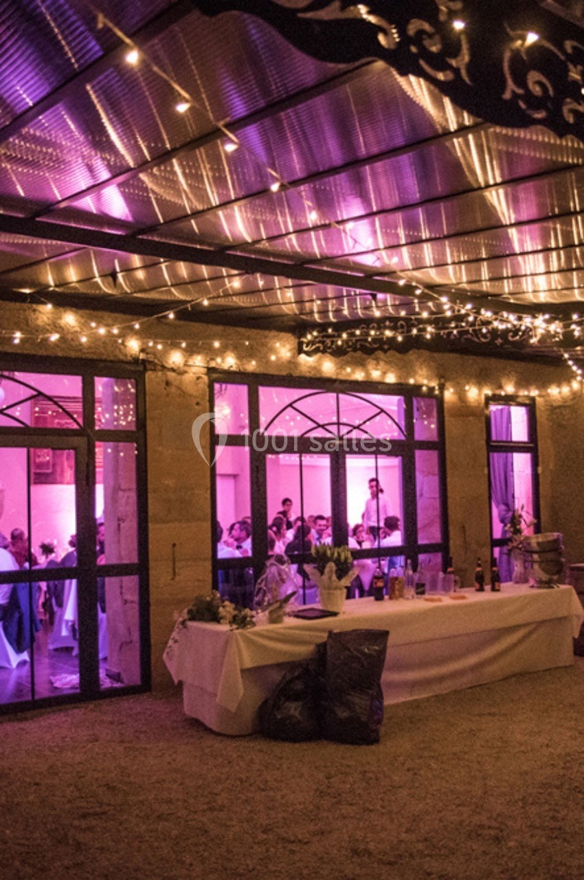 Location salle Roanne (Loire) - Château de Matel #17 Salle de réception éclairée par des lumières violettes et guirlandes, avec des invités visibles à travers les fenêtres.