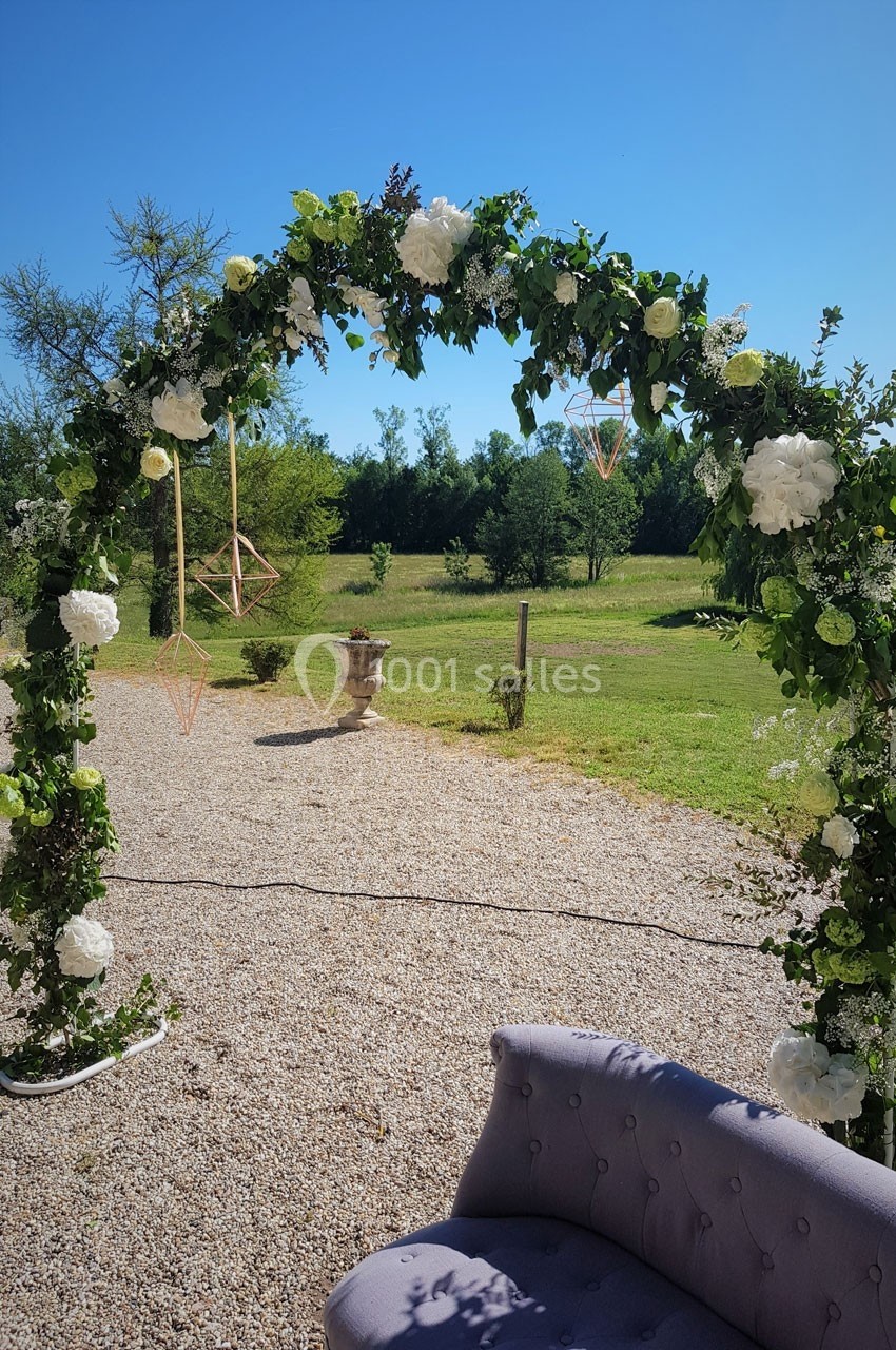 Location salle Roanne (Loire) - Château de Matel #37 Arche fleurie décorée de feuillage et de fleurs blanches, installée en extérieur sur un sol gravillonné.