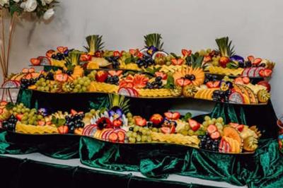 Présentation de desserts variés, notamment des cupcakes et gâteaux, disposés sur des étagères recouvertes de tissu vert.