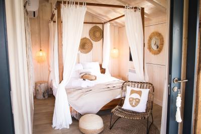 Table en bois décorée de fleurs, bougies et assiettes, installée en extérieur près d'un étang entouré d'arbres.
