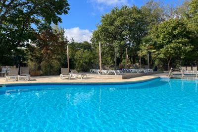 Table en bois décorée de fleurs, bougies et assiettes, installée en extérieur près d'un étang entouré d'arbres.