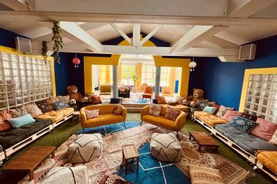 Table en bois décorée de fleurs, bougies et assiettes, installée en extérieur près d'un étang entouré d'arbres.