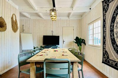 Table en bois décorée de fleurs, bougies et assiettes, installée en extérieur près d'un étang entouré d'arbres.