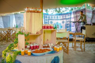 Table en bois décorée de fleurs, bougies et assiettes, installée en extérieur près d'un étang entouré d'arbres.