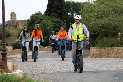 Table en bois décorée de fleurs, bougies et assiettes, installée en extérieur près d'un étang entouré d'arbres.