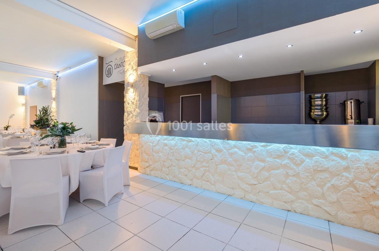 Salle de réception lumineuse avec tables dressées et comptoir en pierre éclairé, décor moderne et épuré.