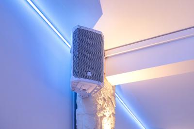 Salle de réception décorée avec des tables rondes, nappes blanches, chaises élégantes et éclairage violet tamisé.
