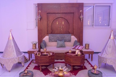 Salle de réception décorée avec des tables rondes, nappes blanches, chaises élégantes et éclairage violet tamisé.