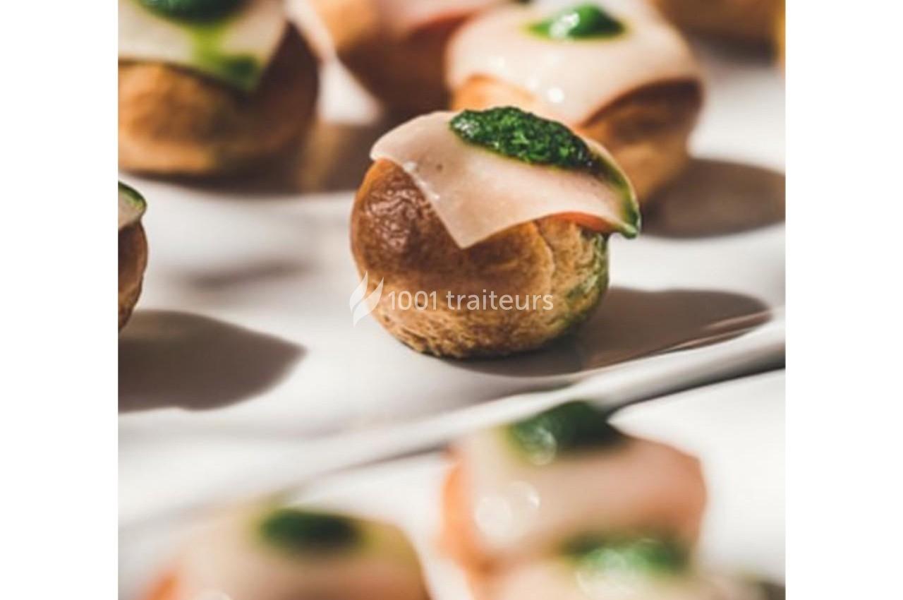 Choux garnis de tranches de jambon et de sauce verte, disposés sur un plateau blanc.