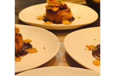 Dés de saumon, ananas et canneberges garnis d'aneth, présentés dans une assiette noire.