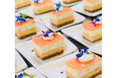 Dés de saumon, ananas et canneberges garnis d'aneth, présentés dans une assiette noire.