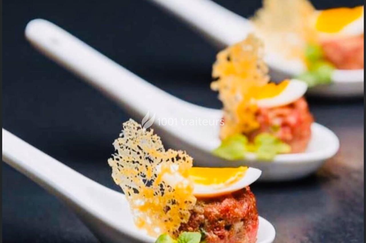 Bouchées gastronomiques servies sur des cuillères en porcelaine, garnies de fromage croustillant et d'herbes fraîches.