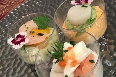 Dés de saumon, ananas et canneberges garnis d'aneth, présentés dans une assiette noire.