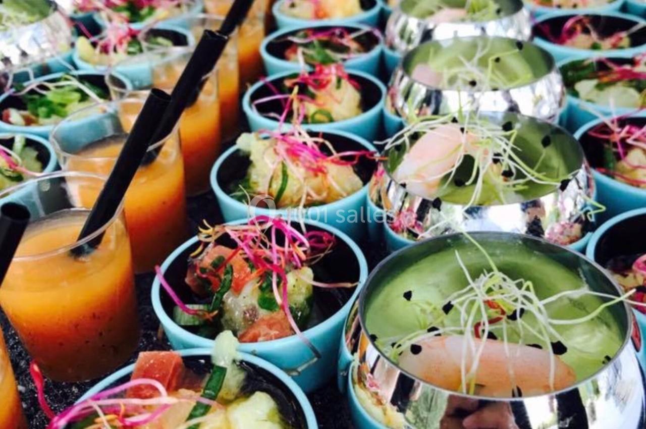 Assortiment de verrines colorées avec gaspacho, salades et garnitures fraîches, présenté sur une table.