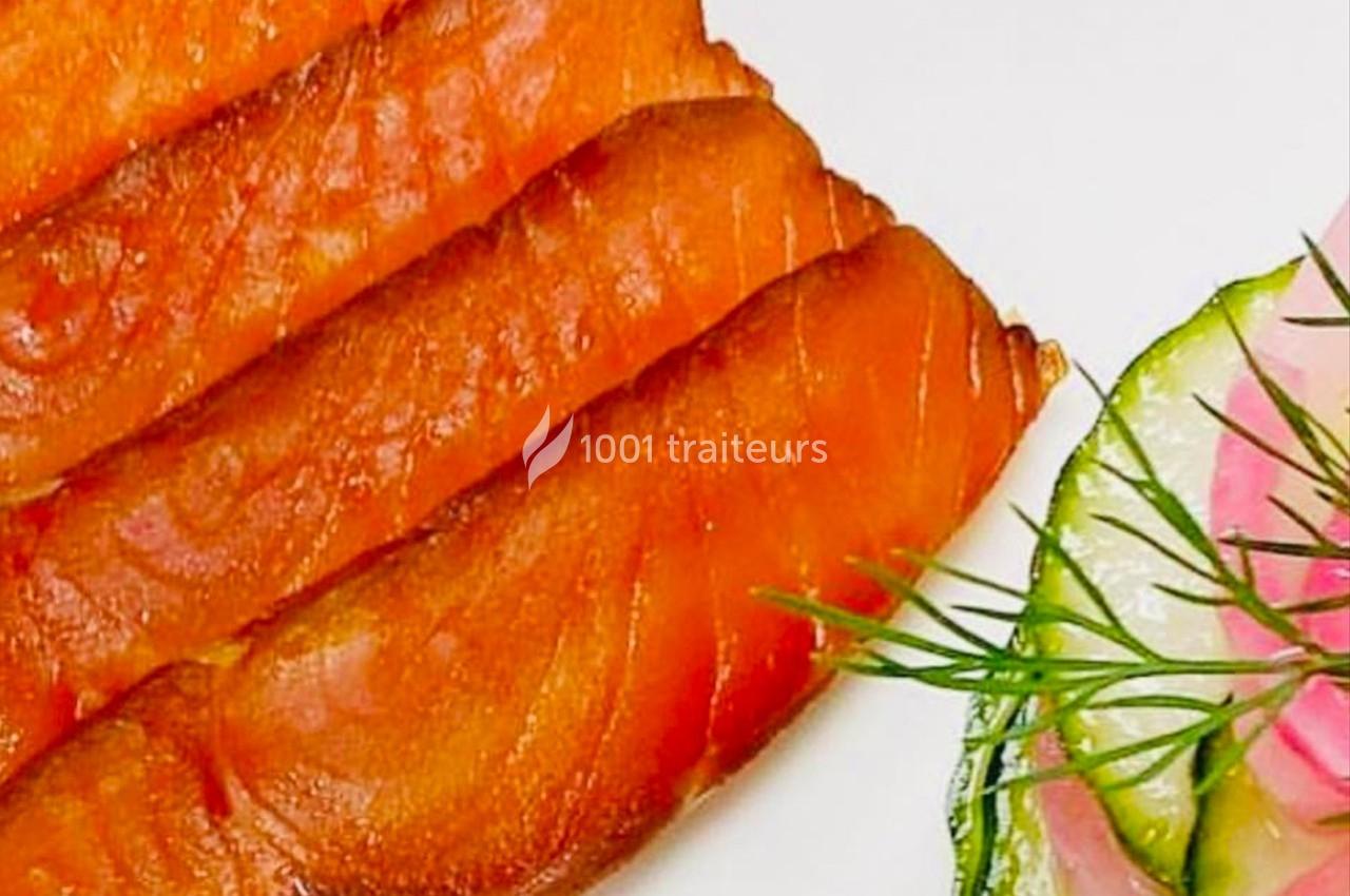 Tranches de saumon fumé disposées à côté de fines rondelles de courgette et d'oignon garnies d'aneth.