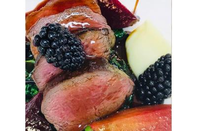 Dés de saumon, ananas et canneberges garnis d'aneth, présentés dans une assiette noire.