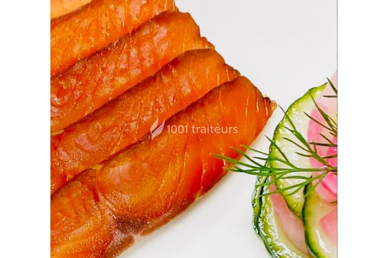 Tranches de saumon fumé disposées à côté de fines rondelles de concombre garnies d'aneth.