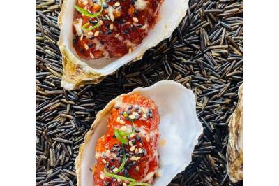 Dés de saumon, ananas et canneberges garnis d'aneth, présentés dans une assiette noire.