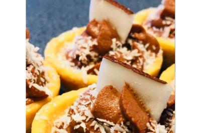 Dés de saumon, ananas et canneberges garnis d'aneth, présentés dans une assiette noire.