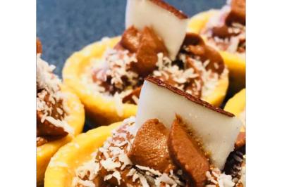 Dés de saumon, ananas et canneberges garnis d'aneth, présentés dans une assiette noire.