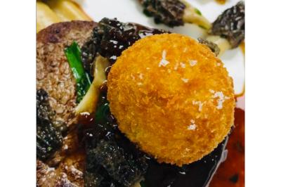 Dés de saumon, ananas et canneberges garnis d'aneth, présentés dans une assiette noire.