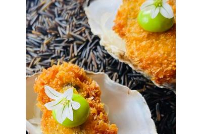 Dés de saumon, ananas et canneberges garnis d'aneth, présentés dans une assiette noire.