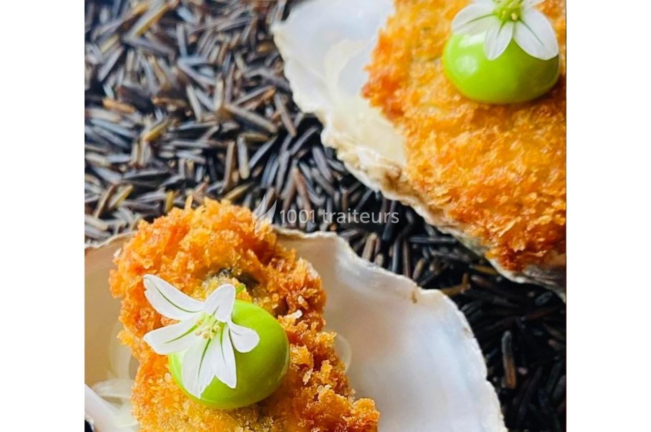 Coquilles garnies de bouchées panées, décorées de fleurs blanches et d'une goutte verte, posées sur du riz sauvage.