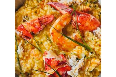 Dés de saumon, ananas et canneberges garnis d'aneth, présentés dans une assiette noire.