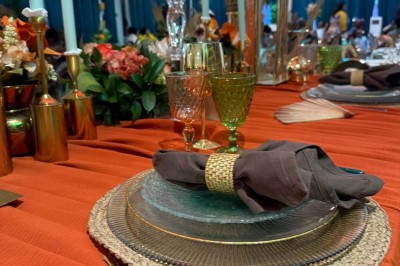 Salle de réception avec table dressée, chaises en bois sculpté, nappes vertes et décorations florales élégantes.
