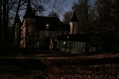 Salle de réception avec tables dressées, chaises noires, murs sombres et un buffet en arrière-plan.