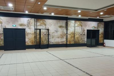 Salle de réception avec tables dressées, chaises noires, murs sombres et un buffet en arrière-plan.