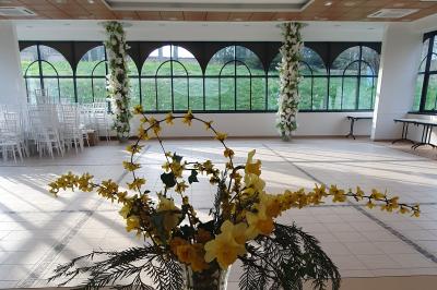 Salle de réception avec tables dressées, chaises noires, murs sombres et un buffet en arrière-plan.